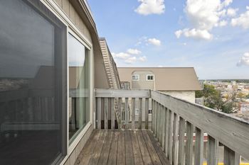 A balcony with a wooden floor and a glass door.